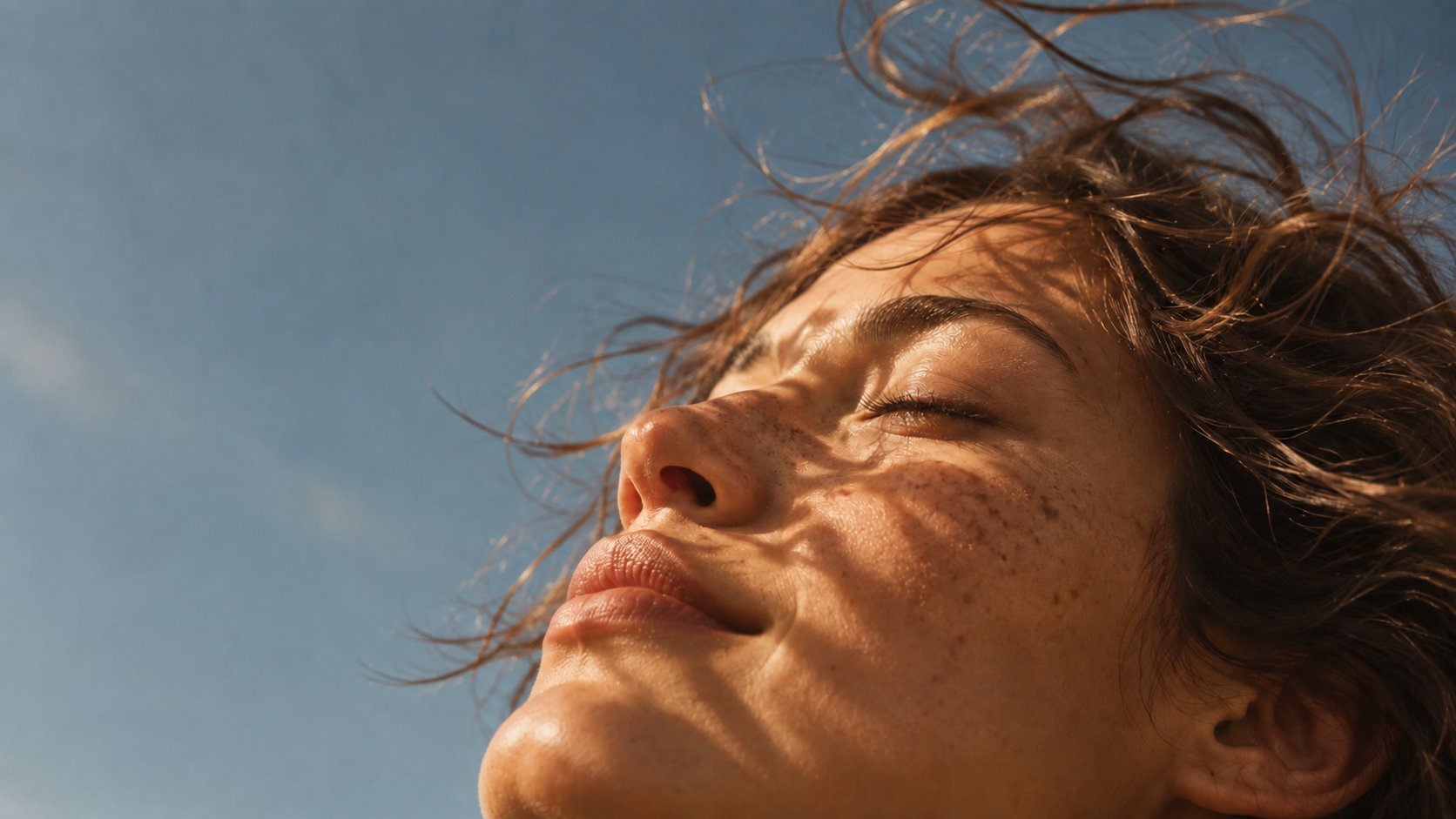 Mulher de olhos fechados ao sol, com o rosto voltado para o céu