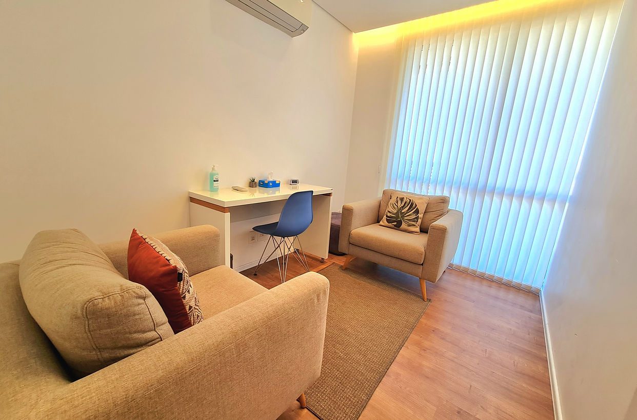 Sala de atendimento com sofá e cortinas claras