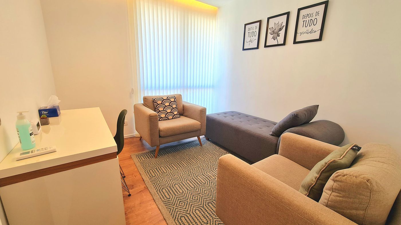 Sala com mesa de trabalho, poltronas e quadros